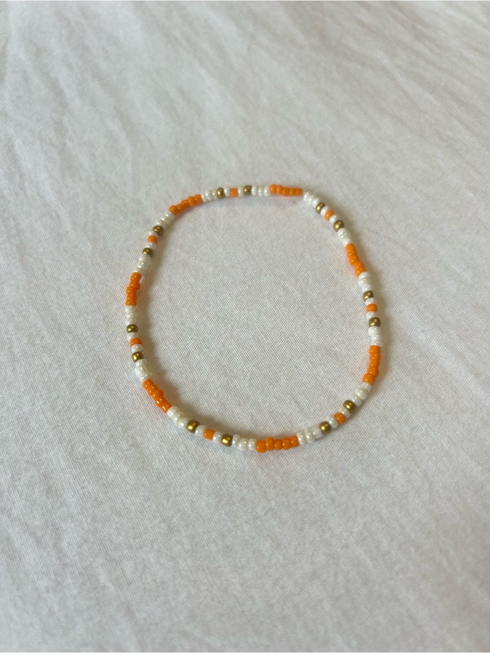 handmade orange and white beaded bracelet with gold accents